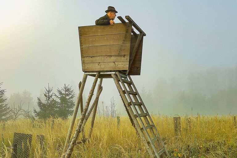 Jäger auf einem Hochstand im Nebel beobachtet das Revier.