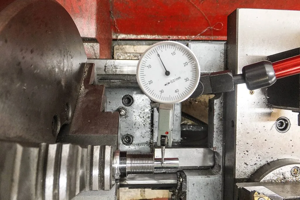 Messung eines geschnittenen Gewindes an einem Metallbauteil mit einer Messuhr auf einer Drehmaschine