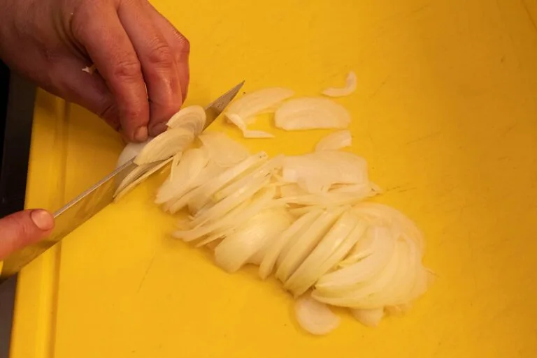Fein geschnittene Zwiebeln auf einem gelben Schneidebrett