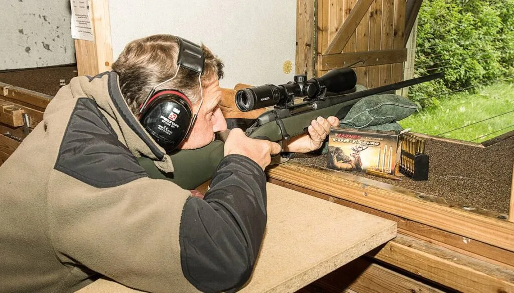 Jäger mit Gehörschutz beim Einschießen einer Büchse mit Zielfernrohr auf einem Schießstand