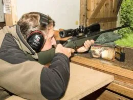 Jäger mit Gehörschutz beim Einschießen einer Büchse mit Zielfernrohr auf einem Schießstand