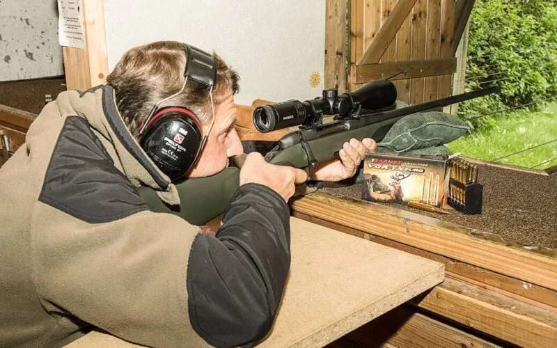 Jäger mit Gehörschutz beim Einschießen einer Büchse mit Zielfernrohr auf einem Schießstand