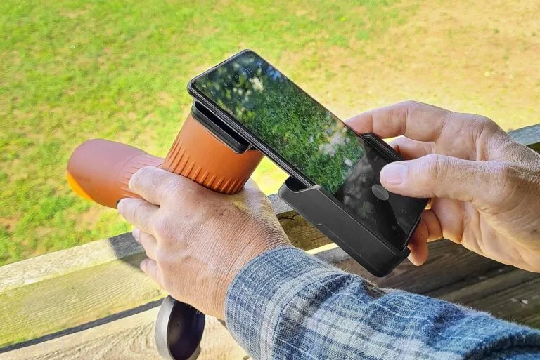 Jäger oder Naturbeobachter befestigt ein Smartphone an ein Spektiv mit Adapter zur digitalen Beobachtung und Fotografie