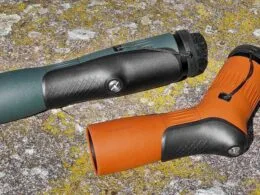 Zwei hochwertige Spektive mit ergonomischer Gummiarmierung in Grün und Braun, liegend auf einer mit Flechten bewachsenen Steinoberfläche