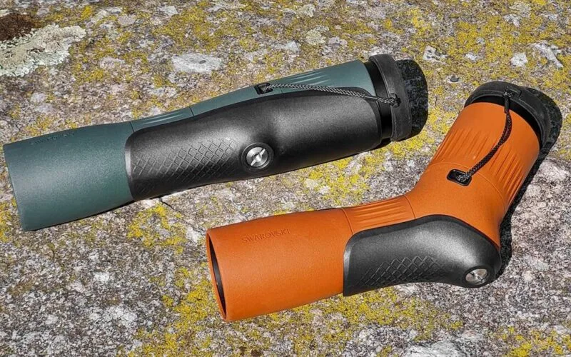 Zwei hochwertige Spektive mit ergonomischer Gummiarmierung in Grün und Braun, liegend auf einer mit Flechten bewachsenen Steinoberfläche