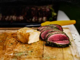 Collage mit Zubereitungsschritten eines gegrillten Hirschrückens mit Kräuterkruste und Polentaschnitten.