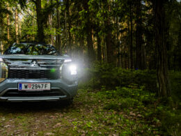 Frontansicht des Mitsubishi Outlander PHEV mit eingeschaltetem LED-Licht im Wald