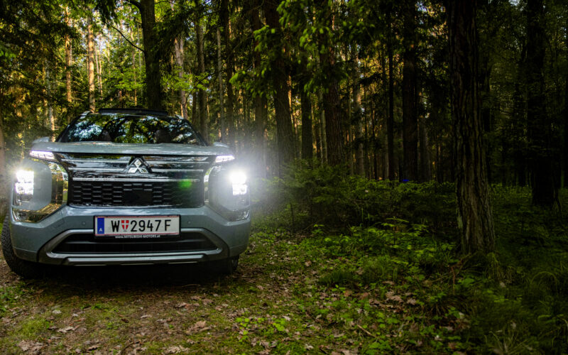 Frontansicht des Mitsubishi Outlander PHEV mit eingeschaltetem LED-Licht im Wald