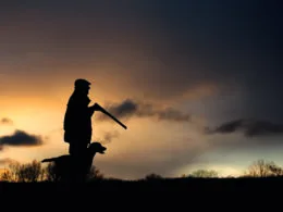 Jäger mit Jagdhund im Sonnenuntergang – Silhouettenaufnahme