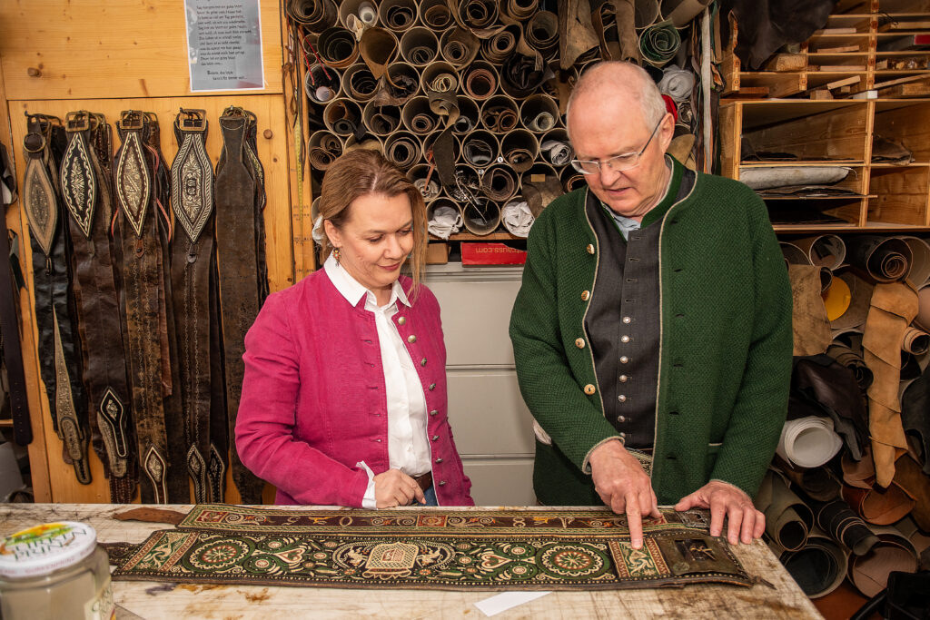 Zwei Personen betrachten einen kunstvoll bestickten Ranzen