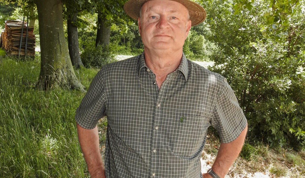 Jäger mit Hut steht im schattigen Waldstück