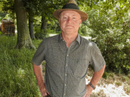 Jäger mit Hut steht im schattigen Waldstück