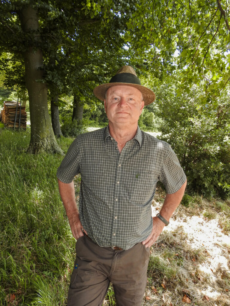 Jäger mit Hut steht im schattigen Waldstück