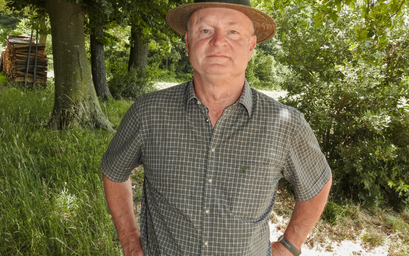 Jäger mit Hut steht im schattigen Waldstück