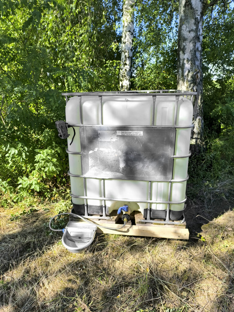 Tränke für Wildtiere im Schatten mit Wasserbehälter im Revier